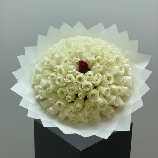 Bouquet of white roses with a red rose in the center on a gray background